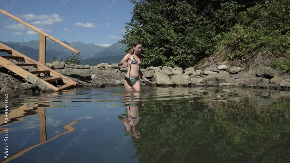 beautiful sexy girl in an open swimsuit bathes in a natural font against the backdrop of huge mountains wide shot beautiful sexy girl in an open swimsuit bathes in a natural font against the backdrop of huge mountains wide shot