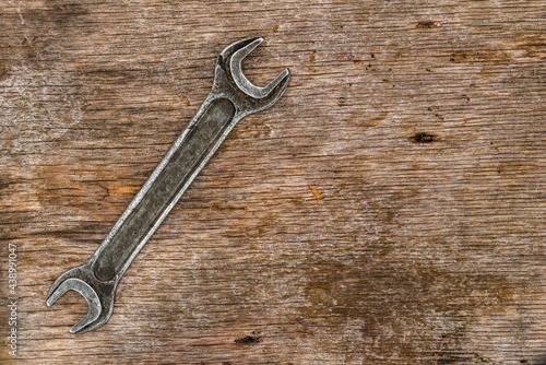 Old wrench on cracked plywood background.