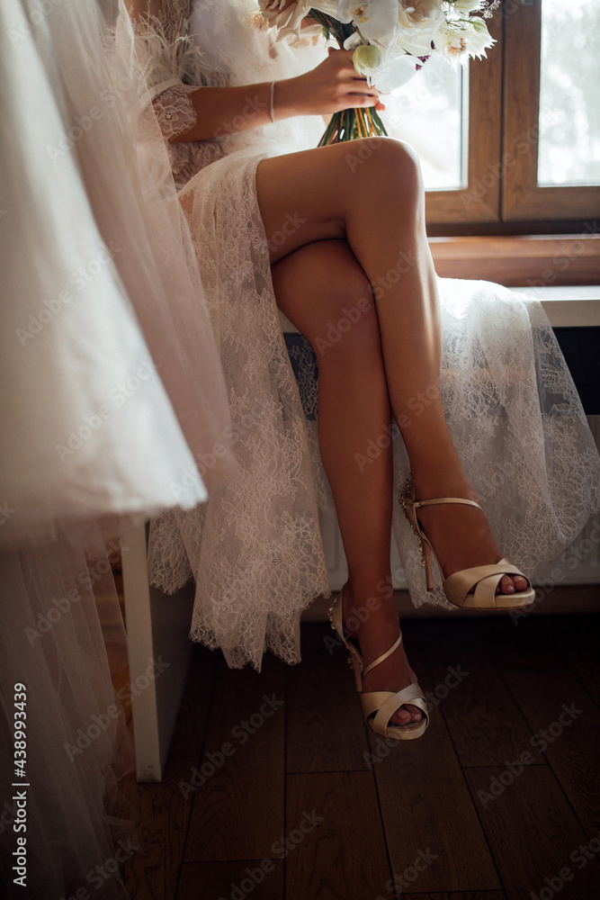 The bride's legs peek out from under the white dress. Bridal accessories.