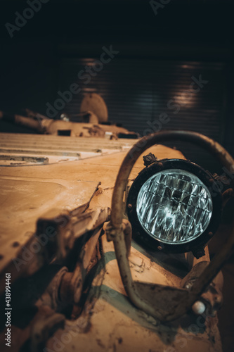 Close up of a headlight of a russian armored personnel carrier, painted in desert orange camo. APC blurred in the background, concepts of war and combat