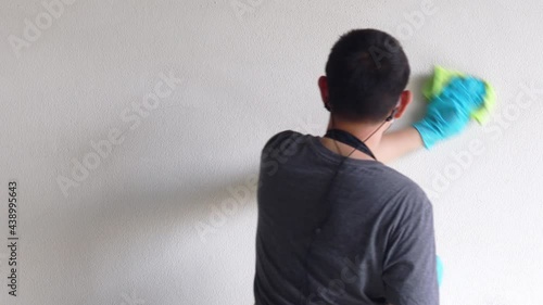 Cleaning staff wipes the walls, use a towel moistened with cleaning solution to rub the wall, Text fill area, White background, Eliminate germs during the virus outbreak.