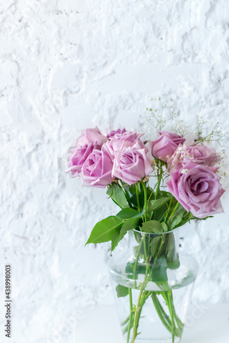 a bouquet of beautiful pink roses in a vase on a white wall background