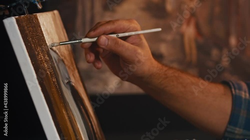 Man artist paints with brush strokes of black paint oil