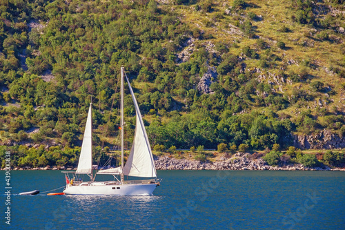 Sailboat sails near shore of Bay of Kotor. Montenegro, Adriatic Sea. Travel concept
