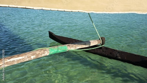 Looking to wooden pole and board of pirogue - typical Madagascar small fishing boat - sailing over clear green sea water photo