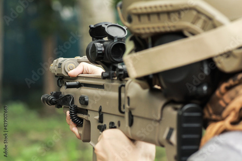Shooter aiming assault rifle at target.