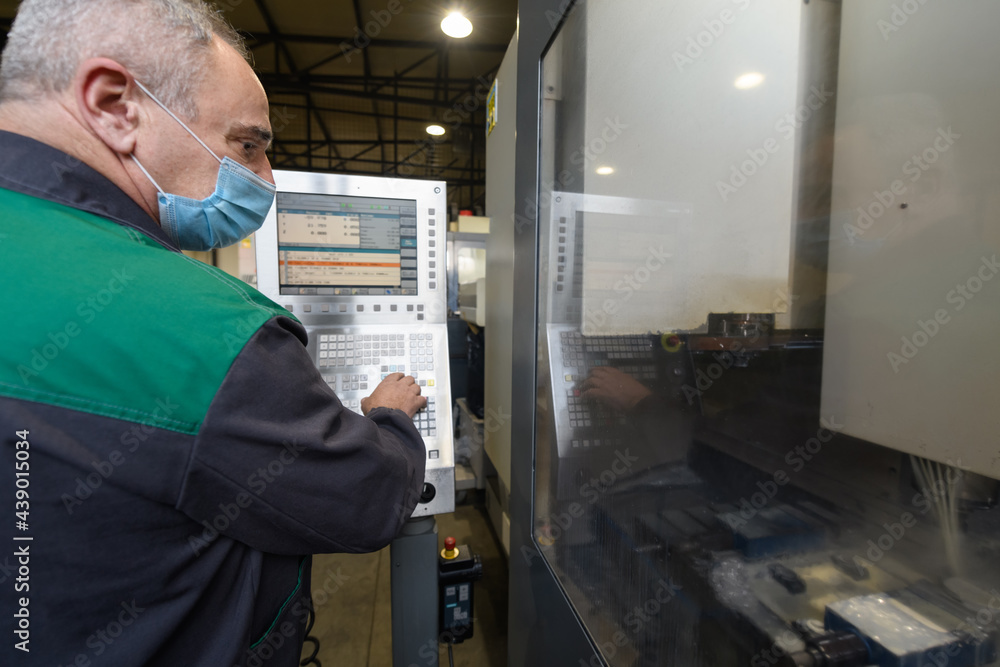 A smart factory worker or engineer wears a face mask because of a pandemic and makes machines in a production workshop. The concept of industry and engineering. A smart factory worker or engineer wears a face mask because of a pandemic and makes machines in a production workshop. The concept of industry and engineering.