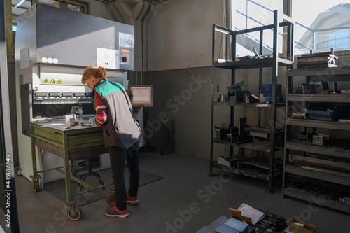 woman working in a modern factory and preparing materia for a CNC machine. 