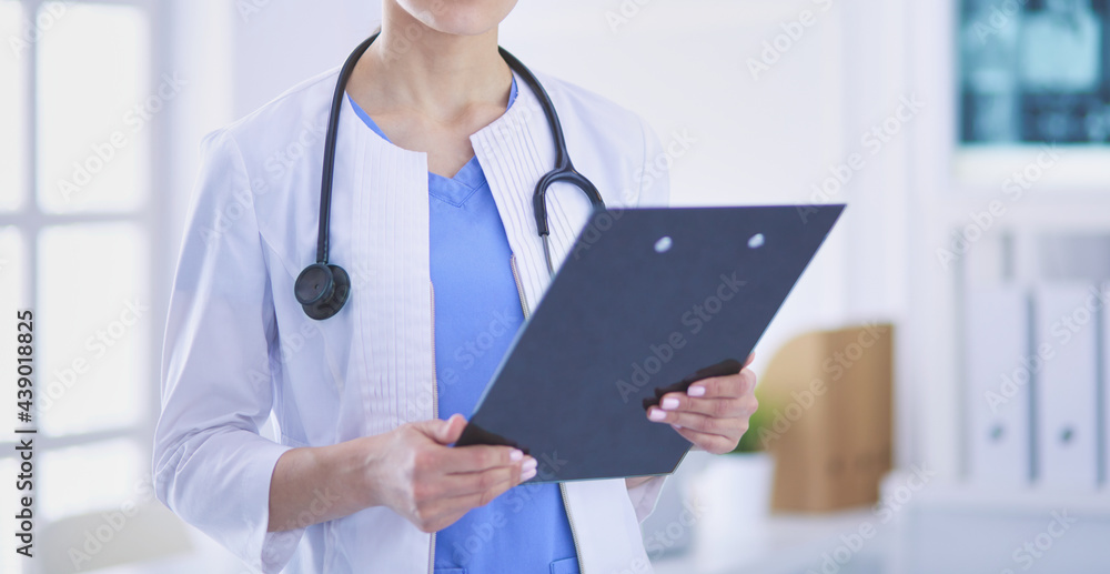 Young smiling female doctor with stethoscope holding a folder at doctor's office Young smiling female doctor with stethoscope holding a folder at doctor's office