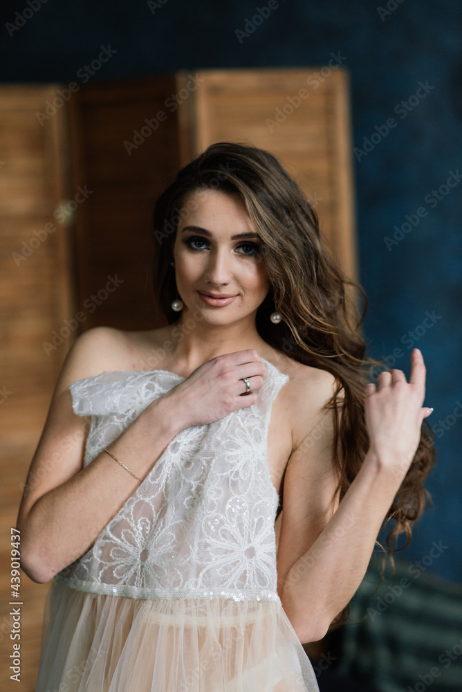 Fototapeta premium Beautiful bride in white lingerie sitting in her bedroom and studio.