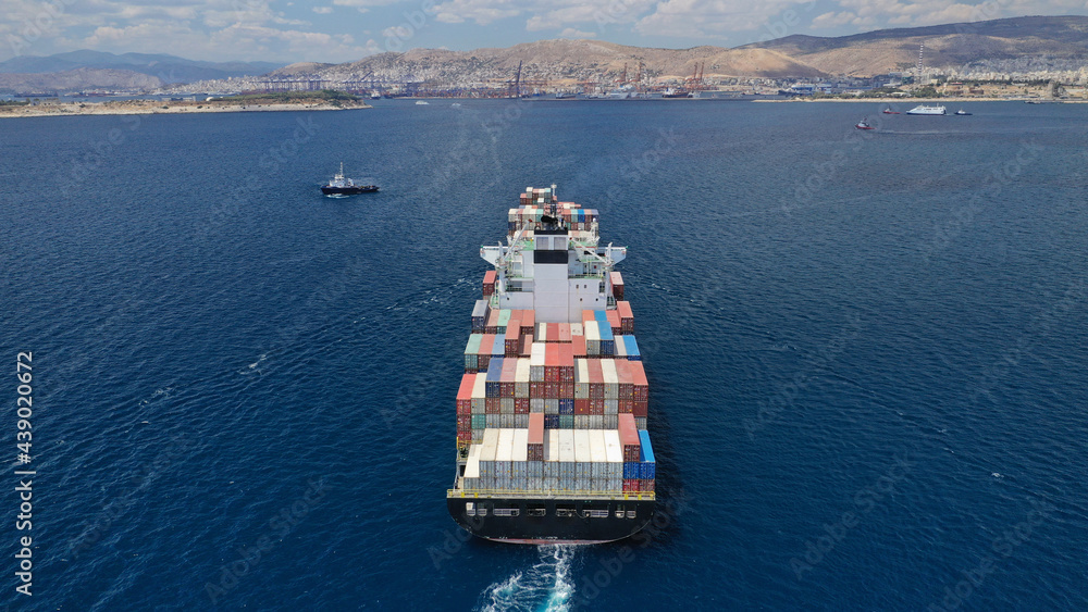 Aerial drone top down photo of industrial colourful vessel carrying heavy truck size containers cruising the Mediterranean deep blue sea