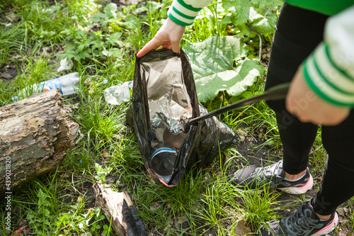 Obraz na plátně Unrecognizable woman collecting trash in the forest after picnic