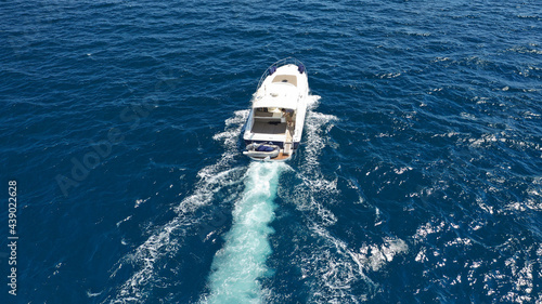 Aerial drone photo of small luxury yacht cruising in deep blue sea near Aegean island, Greece