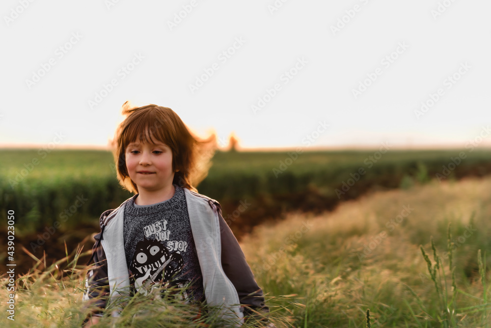 Portrait of a small boy in very green meadow watching the sunset enjoying nature Portrait of a small boy in very green meadow watching the sunset enjoying nature