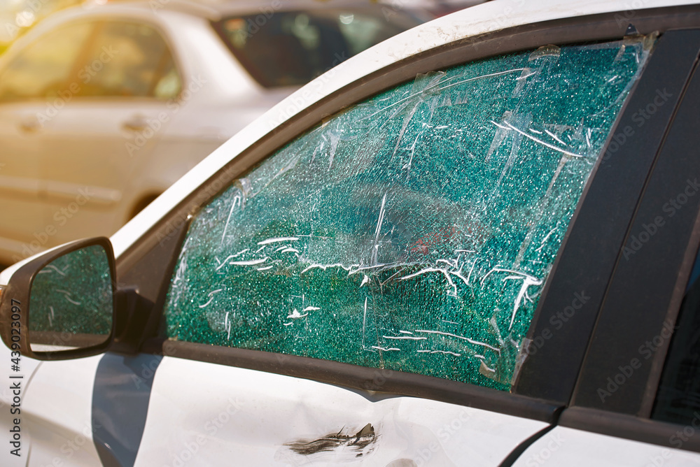 Smashed and cracked side car window glass of parked vehicle. Damaged