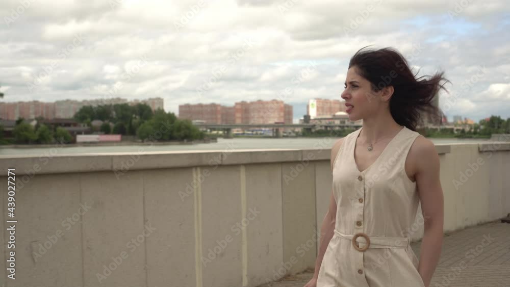 Young attractive woman walks in the city along the embankment river Young attractive woman walks in the city along the embankment river