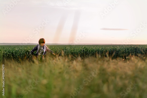 Portrait of a small boy in very green meadow watching the sunset enjoying nature