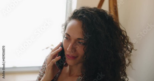 Close up of a woman laughing during a fun conversation over the phone with a friend. Slow motion, handheld. 