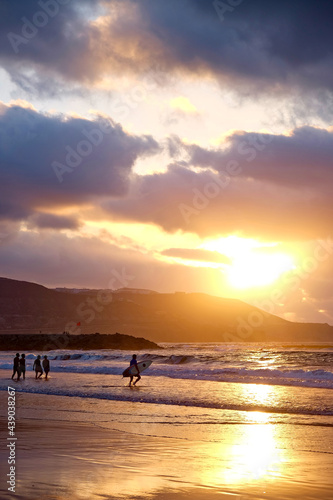 Sunset on the beach, surfers and swimmers in golden glow of the setting sun, las Canteras, Gran Canaria, Canary Islands. © Daguimagery