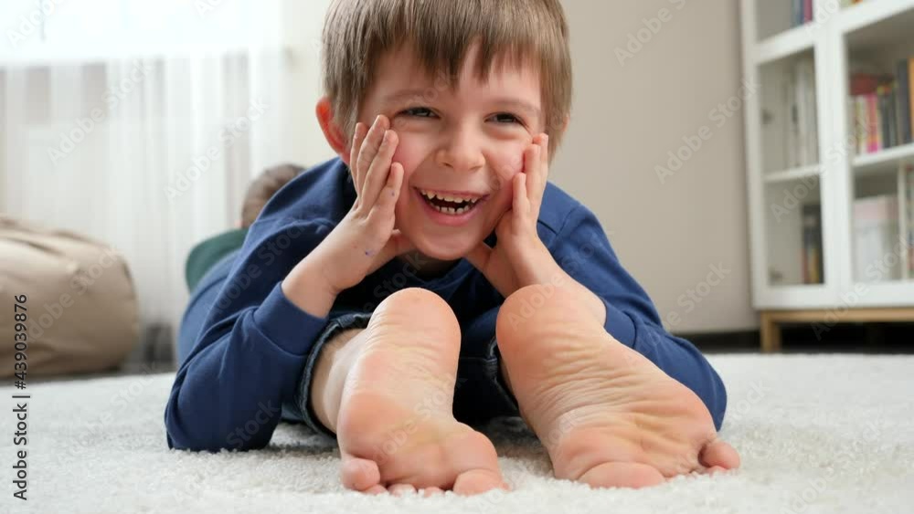 Маленький мальчик рисует с босыми ногами на полу.