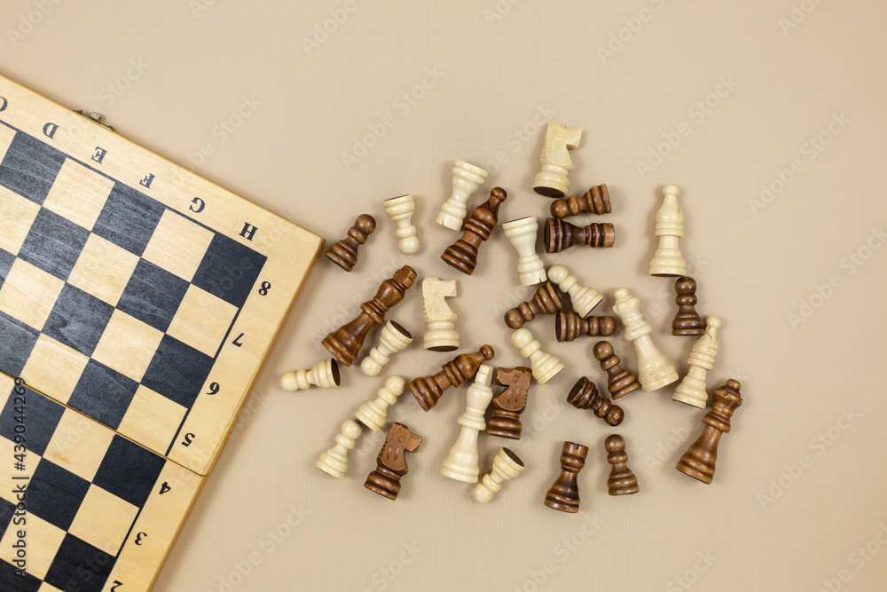 Chess board and chess figures on beige background. Popular logic game for logical thinking. Chess board and chess figures on beige background. Popular logic game for logical thinking.
