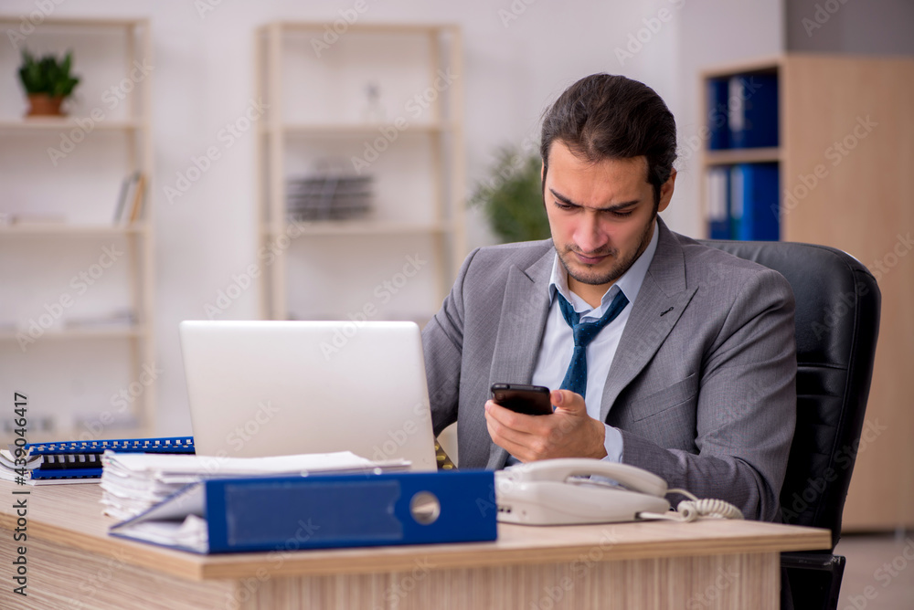 Young male employee unhappy with excessive work in the office Young male employee unhappy with excessive work in the office