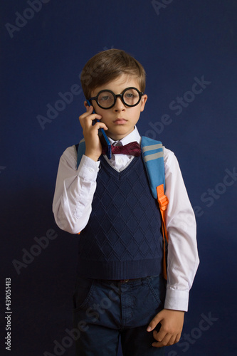 Back to school. Education. A little Schoolboy on dark background with a telefone