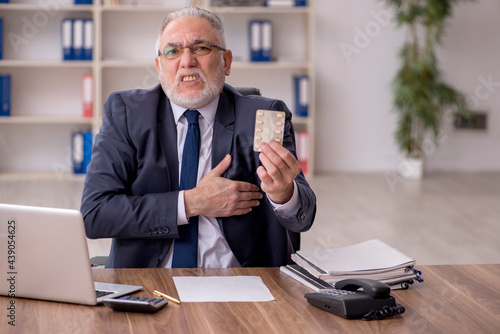 Old ill male employee suffering at workplace