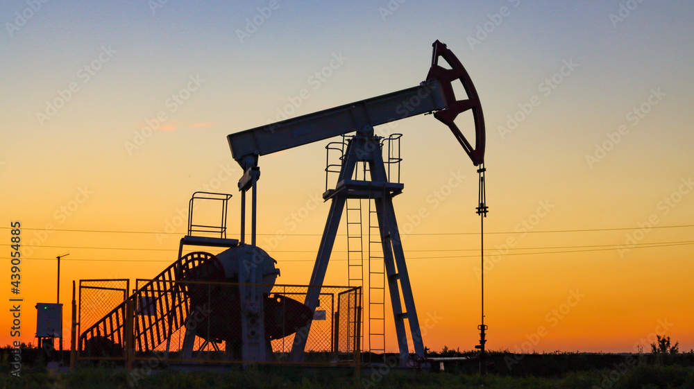 The device of an oil rocker on the background of the sunset. Oil production.
