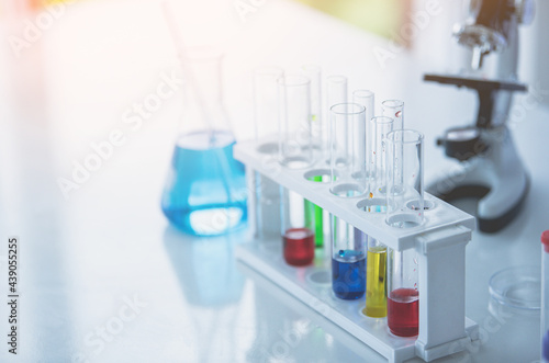 Microscope and colorful test tubes on table in Laboratory. Science chemistry concept. Blue tone © nuttawutnuy