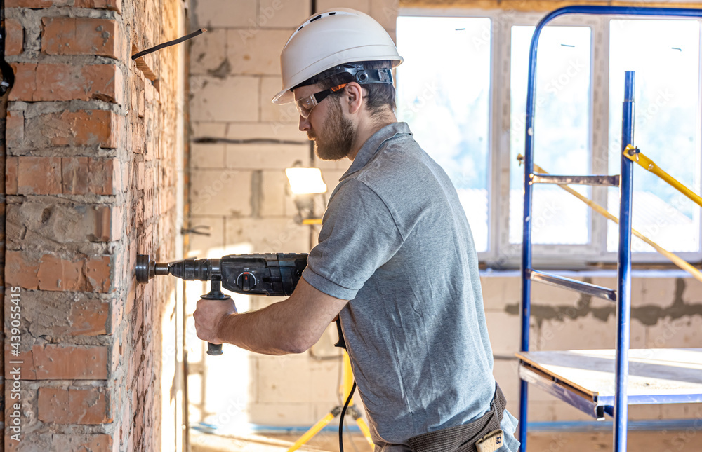 Handyman in the process of drilling a wall with a perforator. Handyman in the process of drilling a wall with a perforator.