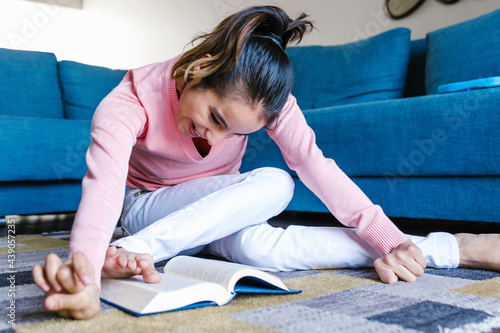 Cuadro en lienzo hispanic disabled girl with cerebral palsy smiling and reading a book at home in
