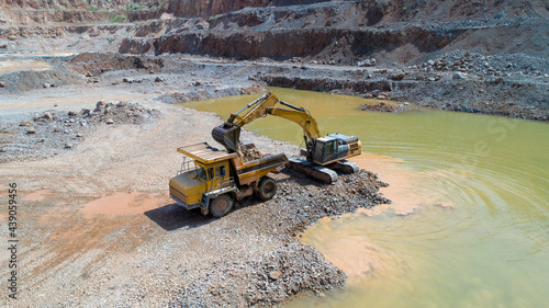 Mining industry. Crawler excavator loads mined ore into a mining dump truck.