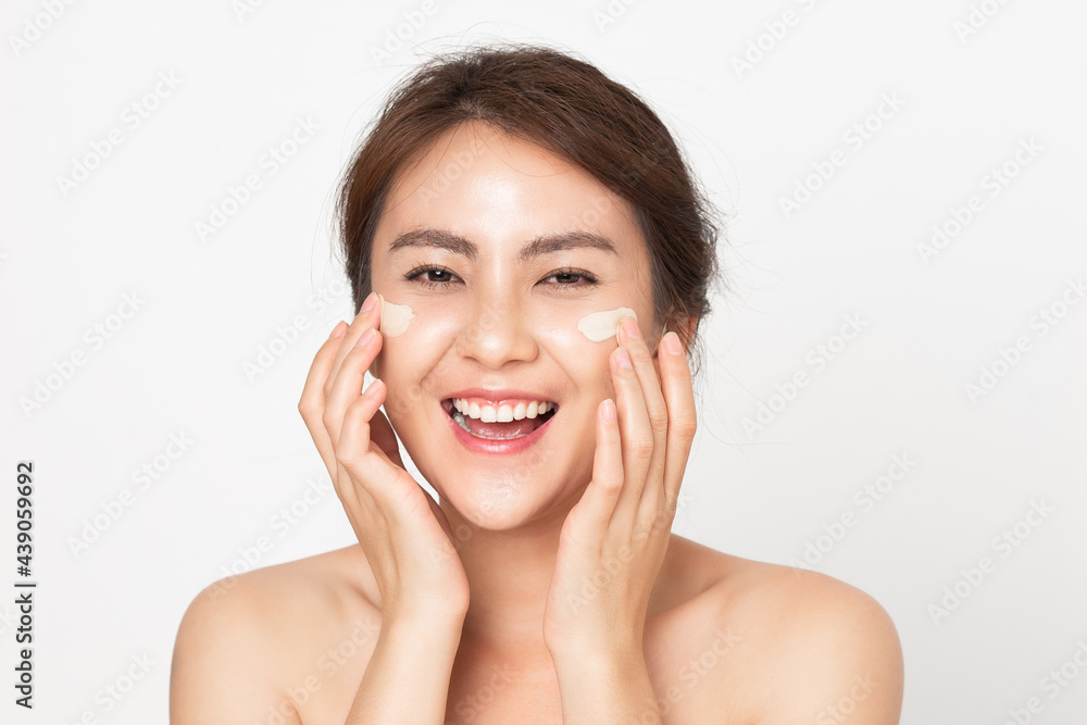 Asian woman looking happy applying cream on her face. Young female applying facial skincare cream. 