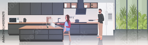 man cooking food woman using laptop couple spending time together stay home coronavirus quarantine