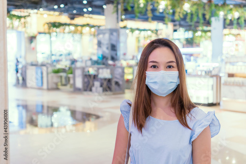 Young Asian woman in blue dress wearing protective fabric mask in department store during Coronavirus, Covid 19 pandemic, New normal lifestyle and Protection measures in public places concept