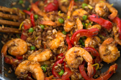 Chinese and Taiwanese homemade street food travel concept. Braised shrimp over fried rice with assorted vegetables for asian or indian lunch menu on the black pan with red peppers and green peace © Valeriia