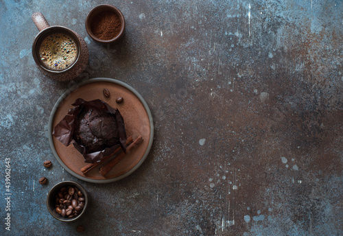 Cup of coffee, chocolate muffin and cinnamone sticks on dark stone background. Flat lay. Copy space