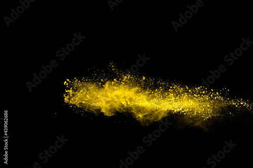 Yellow color powder explosion on black background.