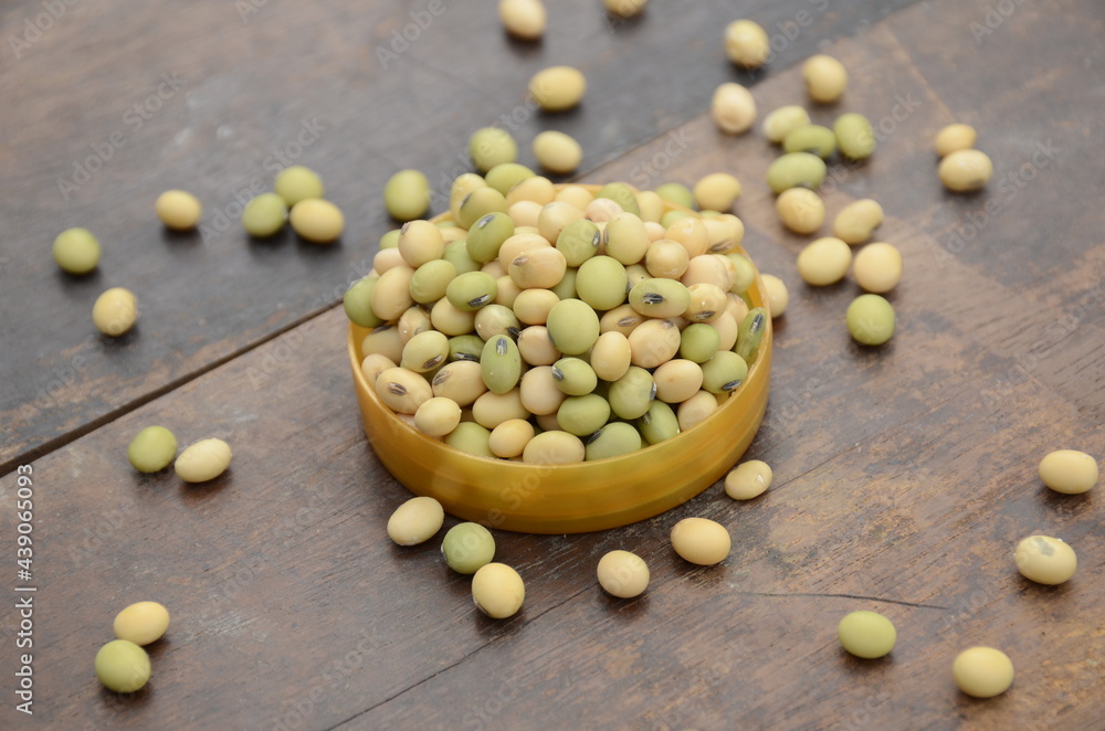 closeup bunch the ripe green yellow soybean in the plastic bowl over out of focus wooden brown background. closeup bunch the ripe green yellow soybean in the plastic bowl over out of focus wooden brown background.