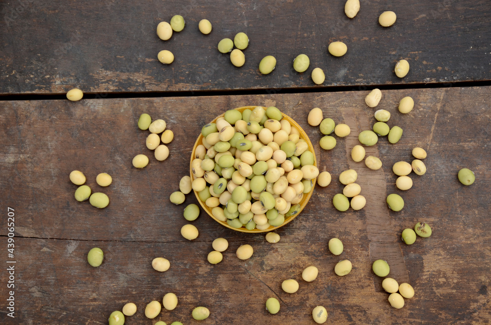 closeup bunch the ripe green yellow soybean in the plastic bowl over out of focus wooden brown background.