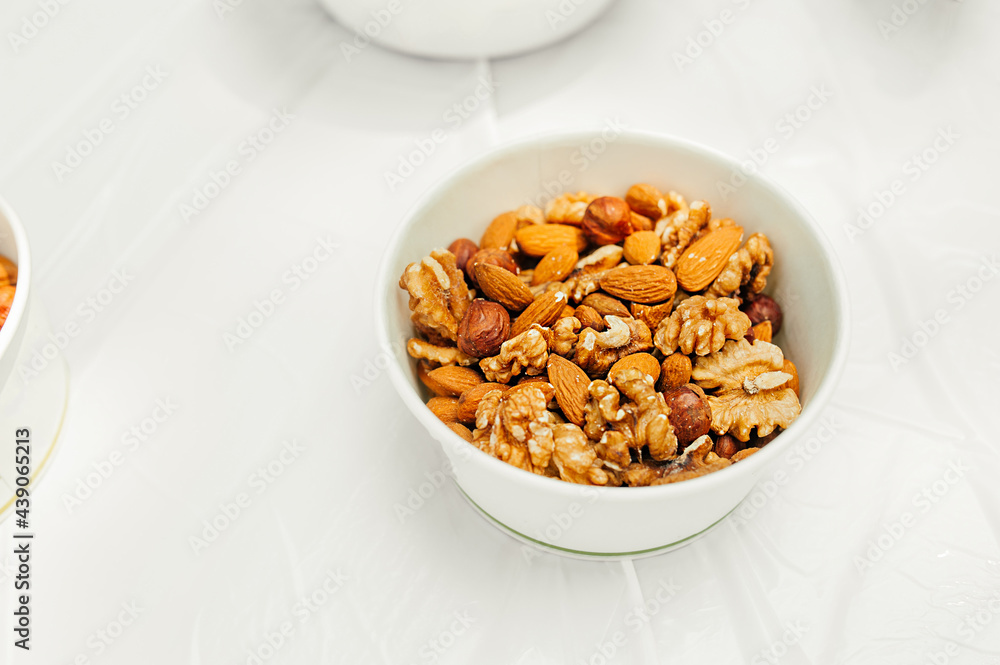 serving plate a mixture of nuts: almonds, hazelnuts, walnuts on light table in an open space. healthy summer raw snacks for a party. healthy lifestyle. selective fous serving plate a mixture of nuts: almonds, hazelnuts, walnuts on light table in an open space. healthy summer raw snacks for a party. healthy lifestyle. selective fous