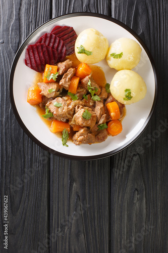 Beef stew with a side dish of boiled potatoes and pickled beets close-up in a plate on the table. vertical top view from above