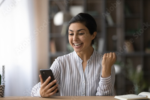 Excellent. Overjoyed indian female college university student receive phone message about winning science fair getting money grant. Lucky young teen lady celebrate shocking news of unexpected victory photo