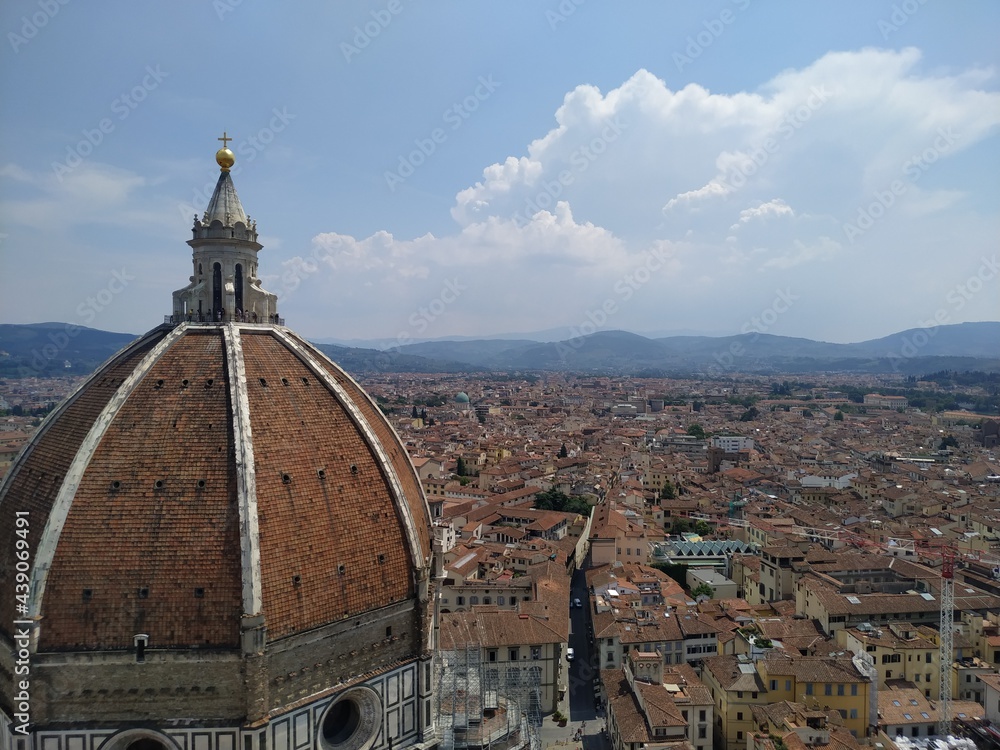 Fototapeta premium Die roten Dächer von Florenz mit Blick auf die Hügel im Hintergrund. Im Vordergrund ist die Kuppel des Doms zu sehen.