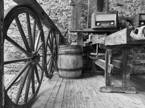 Old household and farm equipment, door keys, pitchforks, rakes, hoes, threshing machines, tube radios, wagon wheels, ladder carts in black and white photography.