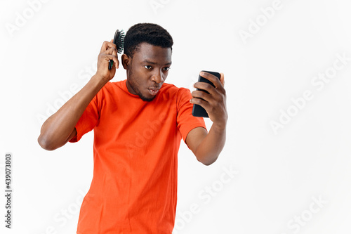 a man with a comb in his hands looks at the phone hairstyle head care