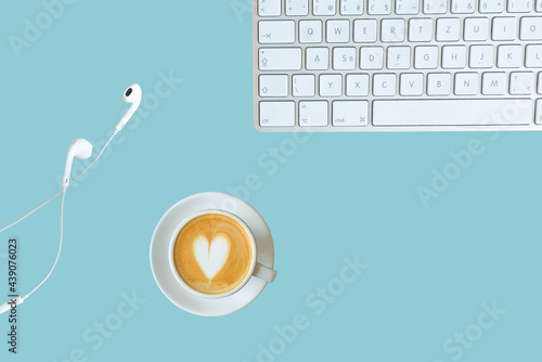 hot coffee in a cup with keyboard and headphones on blue background