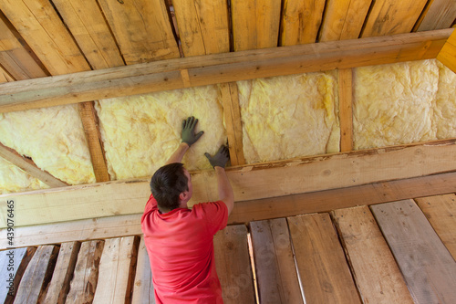 man installing glass wool insulation for new house construction