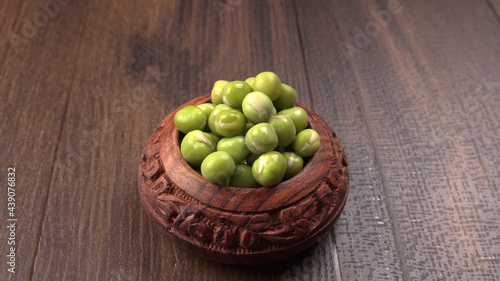 Fresh green peas in wooden bowl on wooden background.